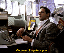 a man in a suit sits at a desk with a typewriter and says oh how i long for a gun