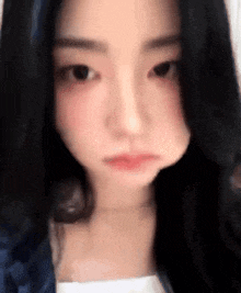 a close up of a woman 's face with long black hair making a face .