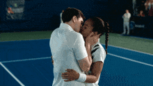 a man and woman kiss on a tennis court
