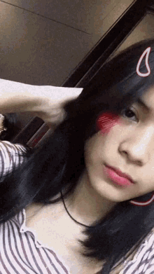 a girl with a red heart on her cheek takes a selfie