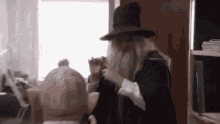 a man with a beard and a hat is standing in a room .