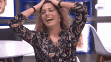 a woman is laughing with her hands in her hair .