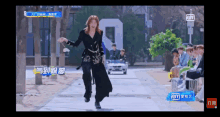a woman in a black dress is dancing in front of a group of people and a sign that says ' iiyi '