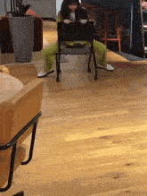 a woman in green pants sits on a chair with her legs crossed