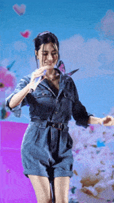 a woman in a denim dress is standing in front of a blue sky