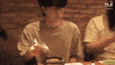 a man is sitting at a table with a spoon in his hand and the word hle on the bottom