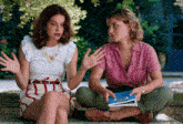 two women sit next to each other on a stone ledge with the letters o visible