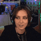 a woman wearing headphones is smiling in front of a microphone and the words elliejoypanic are on the bottom