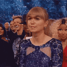 a woman in a blue dress is sitting in a crowd of people .