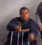 a man with down syndrome is sitting in a chair holding a stick and making a funny face .