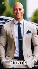 a bald man wearing a tan suit and tie is smiling