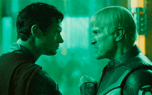 two men are looking at each other and one of them has the letter j on his jacket