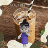 a glass of cold brew with a straw and a cartoon character wearing a zhout shirt