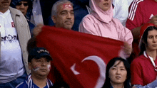 a man wearing a headband with the letter c on it holds a turkey flag