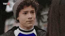 a young boy wearing a beanie and a blue shirt with trt1 on the bottom left
