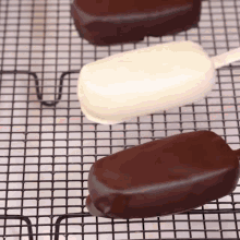 three chocolate covered ice cream bars are sitting on a wire rack