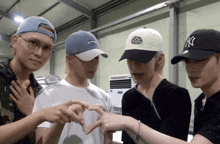 a group of young men wearing ny hats are making a heart with their hands