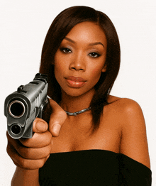 a woman in a black dress is pointing a gun