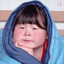 a little girl is wrapped in a blue blanket with chinese writing on it