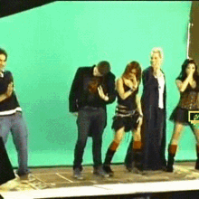 a group of people standing on a stage with a green screen behind them