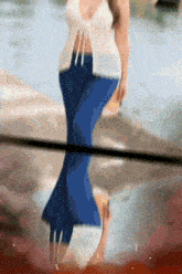 a woman in a white top and blue pants is reflected in a window
