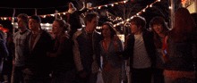 a group of people are standing in a crowd and one of them is wearing a jacket that says ' a ' on it