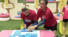 two women wearing red shirts with the word rise on them are playing a game