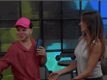 a woman in a red hoodie is hugging another woman in a white tank top