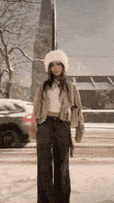 a woman wearing a white fur hat is standing in the snow