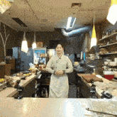 a woman in a white apron is standing at a counter in a restaurant