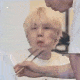 a man is feeding another man with chopsticks while making a funny face .