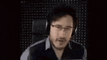 a man wearing headphones is standing in front of a wall with holes in it .