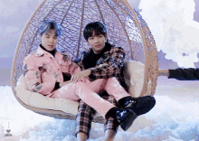 two boys are sitting in a wicker chair in the clouds .