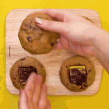 a person is putting a cookie on a wooden cutting board ..