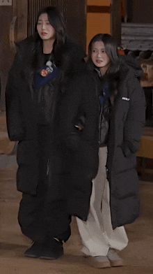 two girls are standing next to each other wearing long black coats with the word berry on them