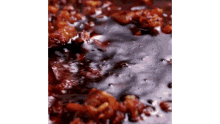 a close up of a sauce that is being poured into a pan of food .
