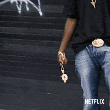 a man wearing a black shirt and blue jeans is walking down stairs with a netflix logo on the bottom right