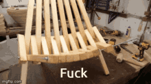 a wooden chair is sitting on a table with the words fuck written on it