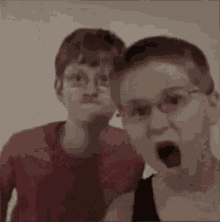 two young boys wearing glasses are making funny faces while standing next to each other .