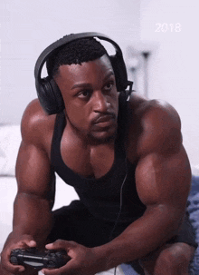a man wearing headphones is playing a video game with the year 2018 behind him
