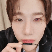a close up of a person 's face with red eyes holding a microphone