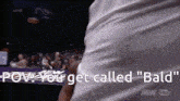 a man in a white shirt is standing in front of a crowd and says " prove you get called " bald "