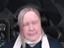 a man wearing headphones and a scarf around his neck is making a funny face .