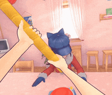 a person holding a yellow stick in front of a cat