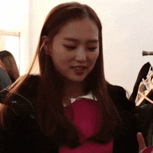 a woman wearing a black jacket and a pink shirt is standing in front of a rack of clothes