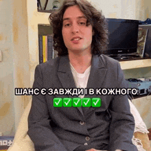 a man in a suit is sitting in front of a tv and a sign that says " shanc "