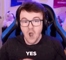 a man wearing glasses and headphones is making a funny face while sitting in a gaming chair .