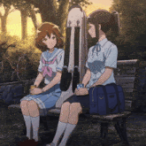 two anime girls are sitting on a bench with a case