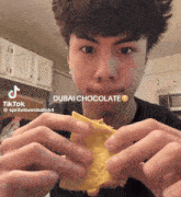 a young man is eating a taco with a dubai chocolate face on it