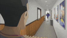 a man is looking down a hallway with posters on the wall including one that says ' a ' on it